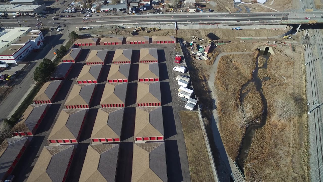 Overhead industrial block with storage rows, road traffic area, and dry open ground.