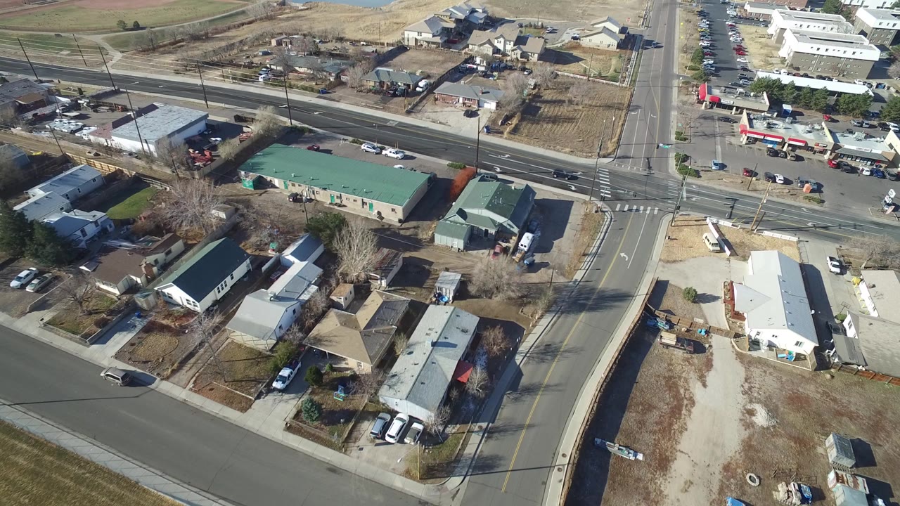 A bird's-eye frame over Hidden Lake, Colorado shows a four-way road intersection, parked cars, green-roofed buildings, bare trees, dry lots, and no visible people.