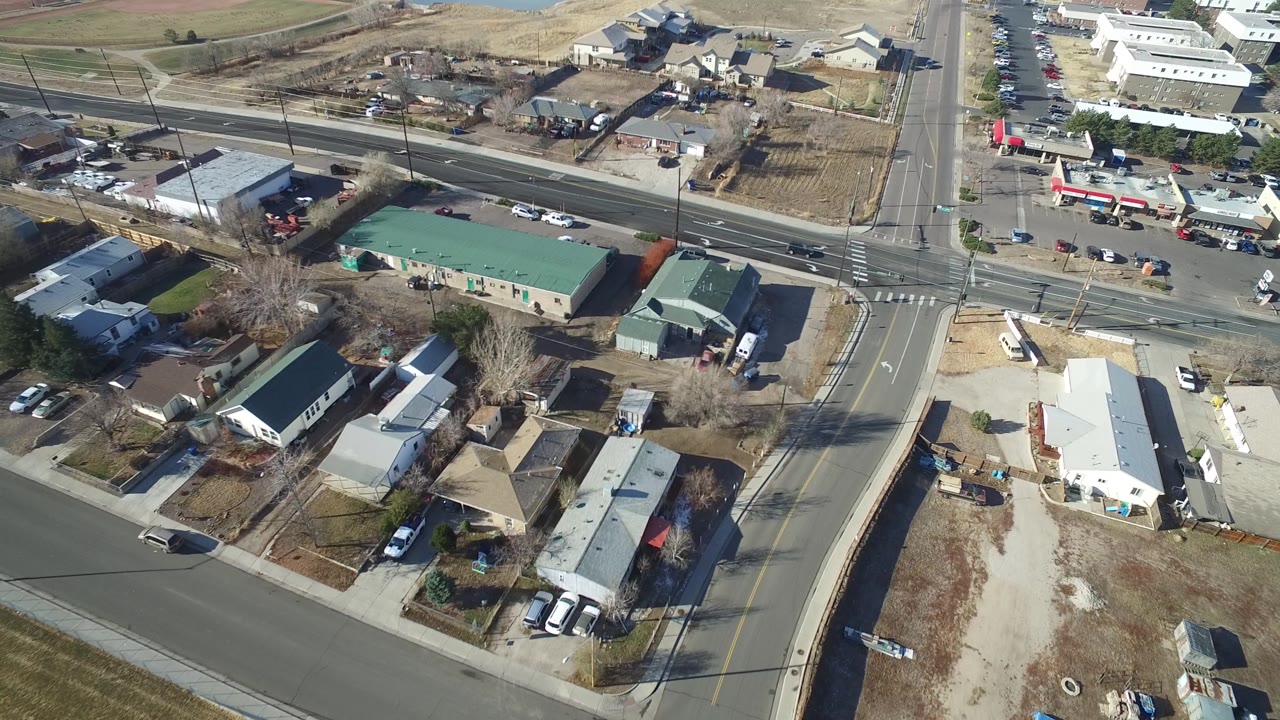 The next Hidden Lake, Colorado aerial frame keeps the road junction central, with vehicles on both streets, parking areas, low buildings, open dirt lots, and no visible people.
