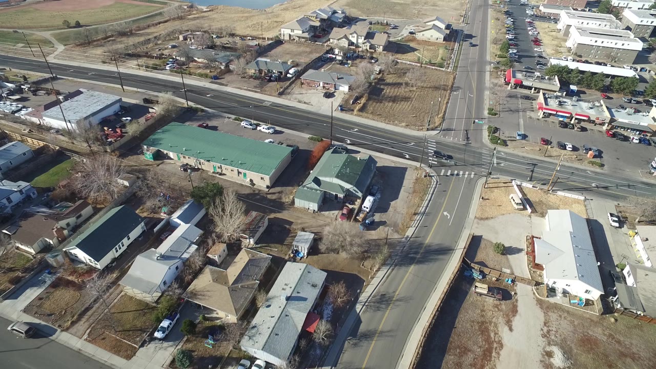 Drone-style overhead view of an intersection beside dry lots and buildings.