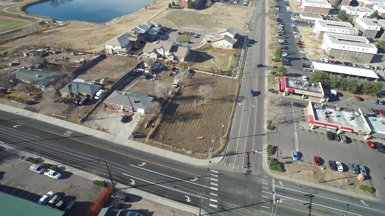 Aerial view of an intersection, homes, cars, and a pond
