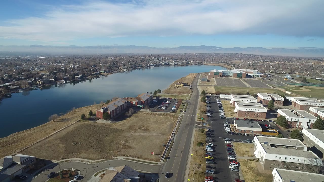 Aerial view of a lake beside industrial buildings and a straight road.