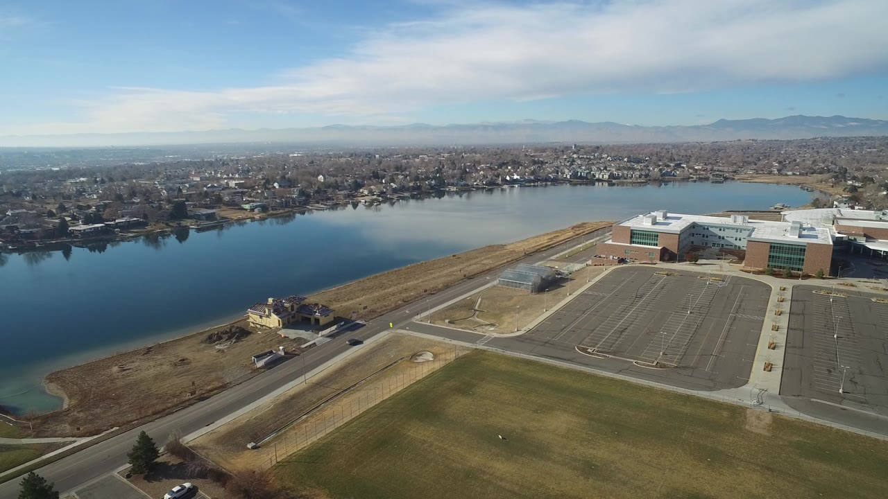 Aerial view of a lake, road, parking lot, and industrial buildings.