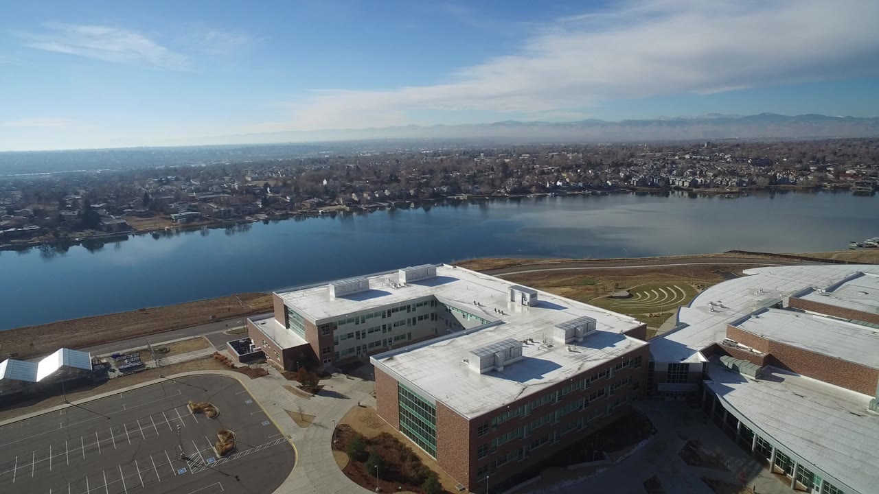 Aerial view of white-roofed buildings beside a broad blue lake.