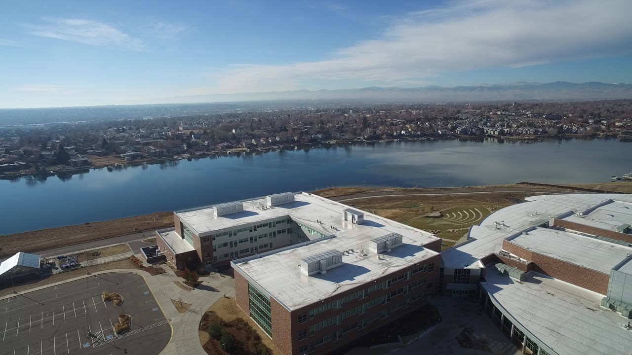 Drone-height view across rooftops toward a lake and distant homes.