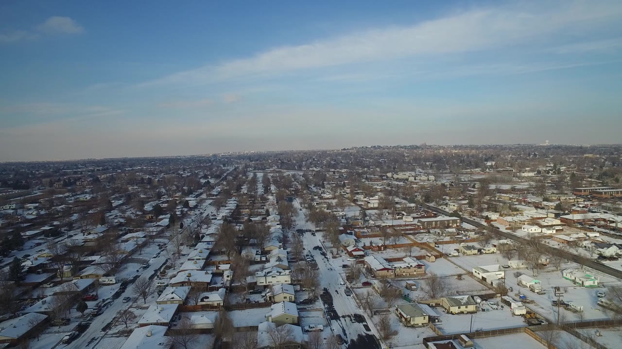 High aerial view over Hidden Lake, Colorado showing snow-covered homes, straight residential streets, leafless trees, and a distant low skyline with no visible people.