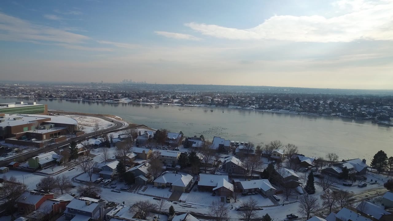 Snow-dusted suburb and waterfront seen from above with a hazy skyline in the distance.