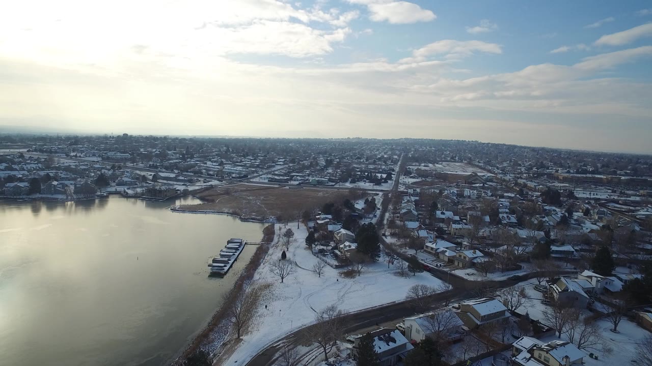 Aerial view of snowy lakeside homes and a broad town horizon.