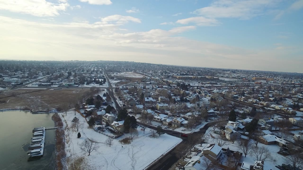 Aerial view of snowy lakeside neighborhood with docks and distant homes