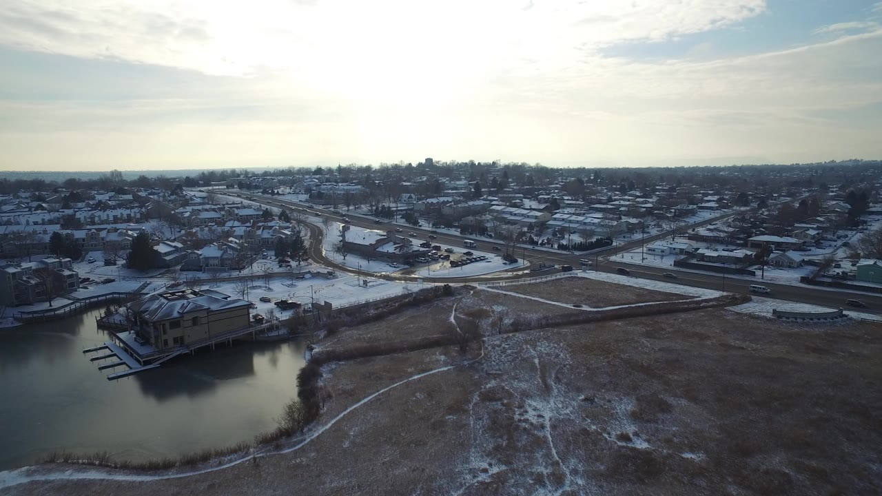 Aerial view of snowy lakeside homes and curving roads.