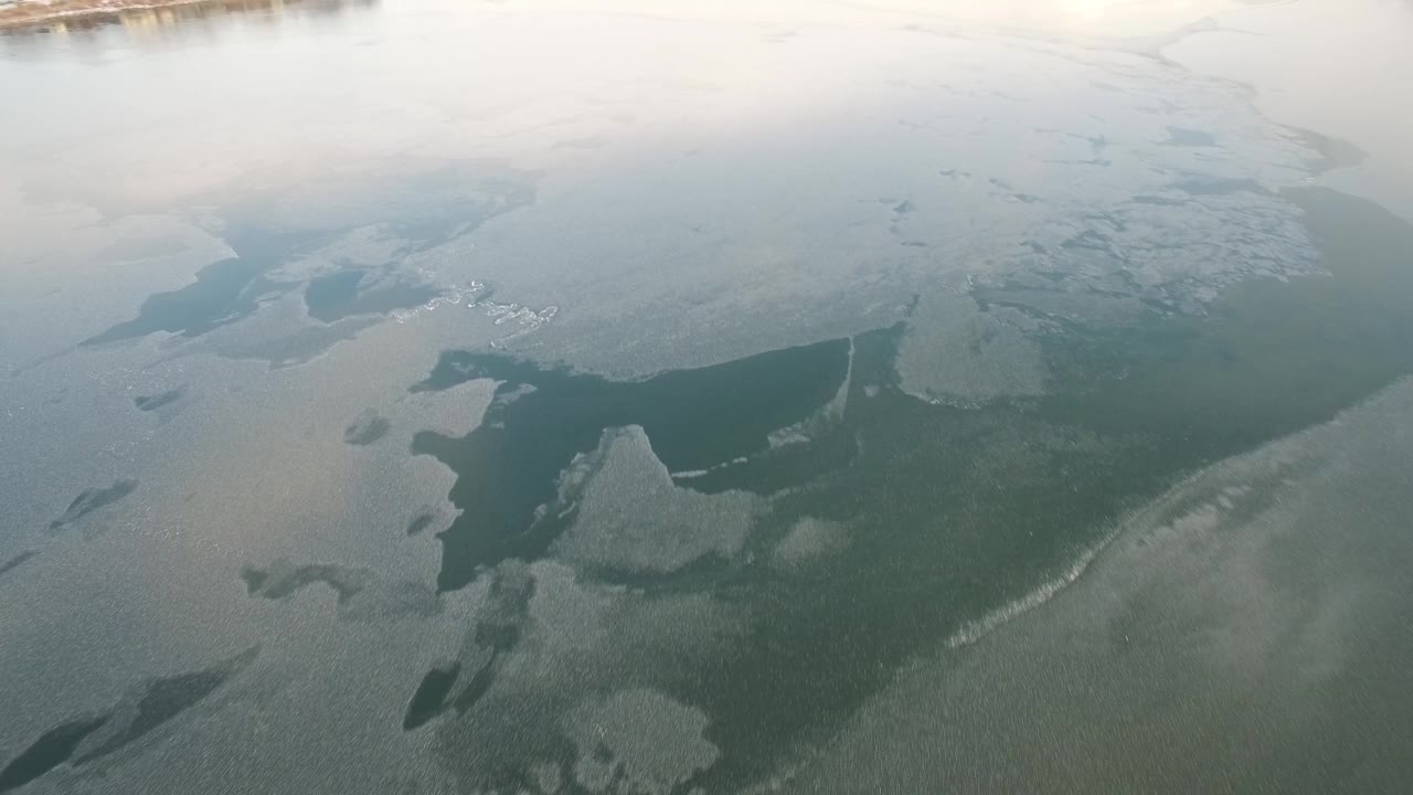 Aerial view of Hidden Lake, Colorado, with irregular gray-white ice plates crossing darker water and no visible people.