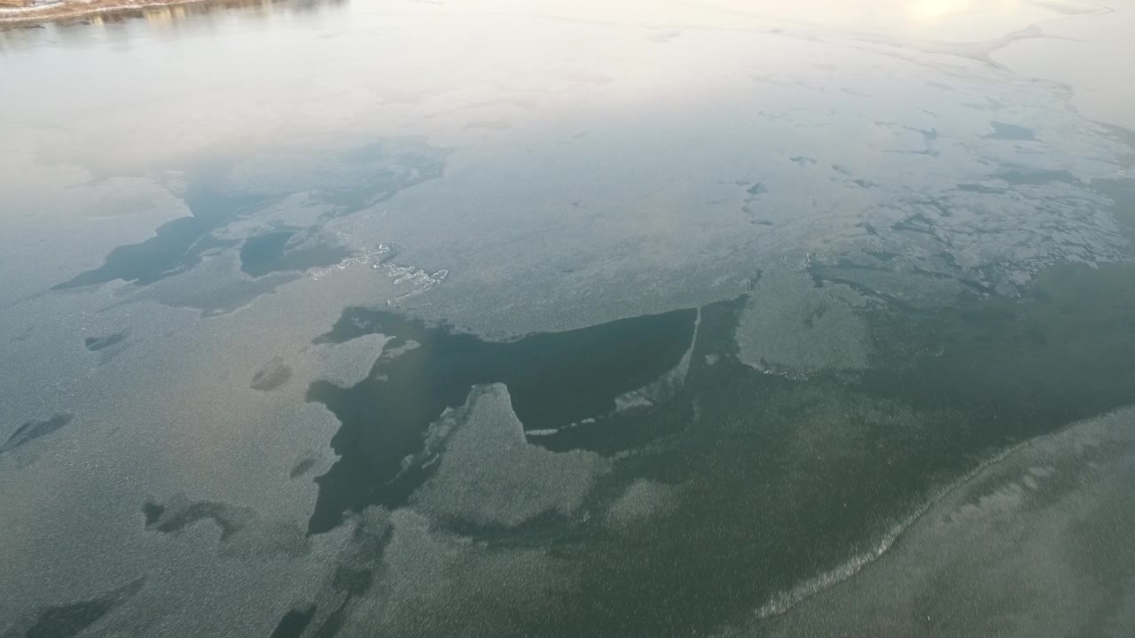 Frozen lake surface with large dark channel and pale ice.