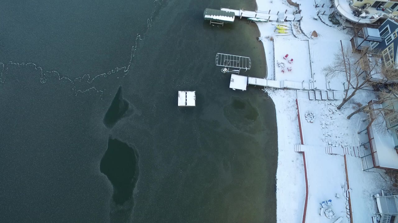 Overhead view of frozen lake beside snow-covered lakeside homes