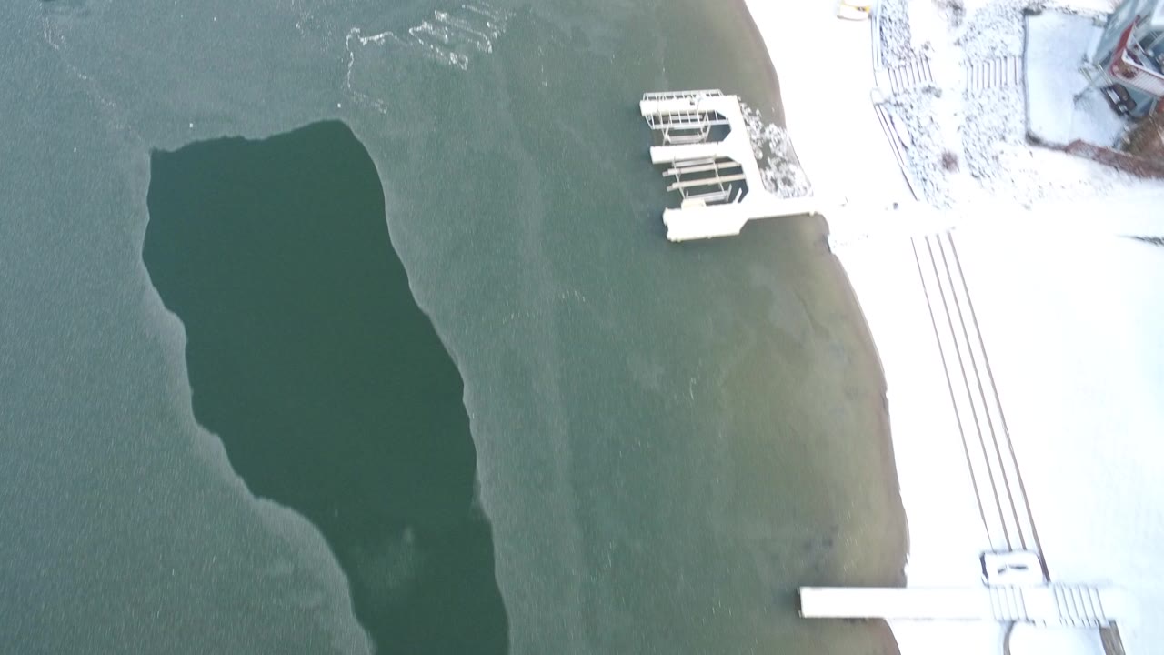 Overhead frozen lake beside snowy shoreline and pier