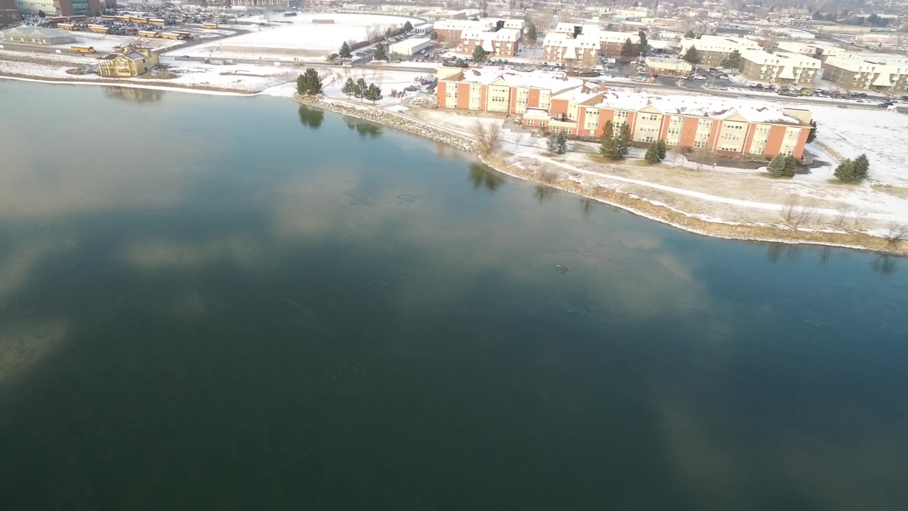 Hidden Lake, Colorado appears from above with broad water, a curved snowy bank, tan and red residential buildings, roads, and no visible people.
