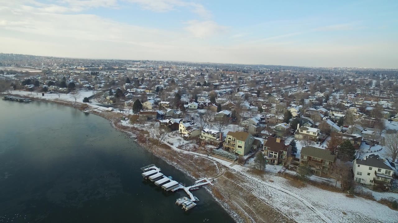 Snowy lakeside houses seen from above beside dark water.