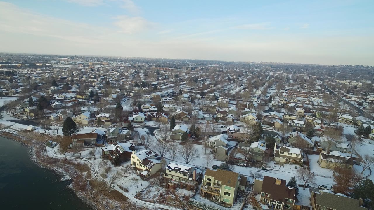 Snowy lakeside neighborhood seen from above with water at left