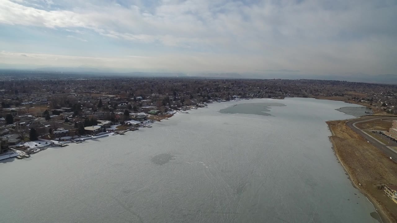 Aerial view over a broad lake with neighborhoods along the far shoreline.