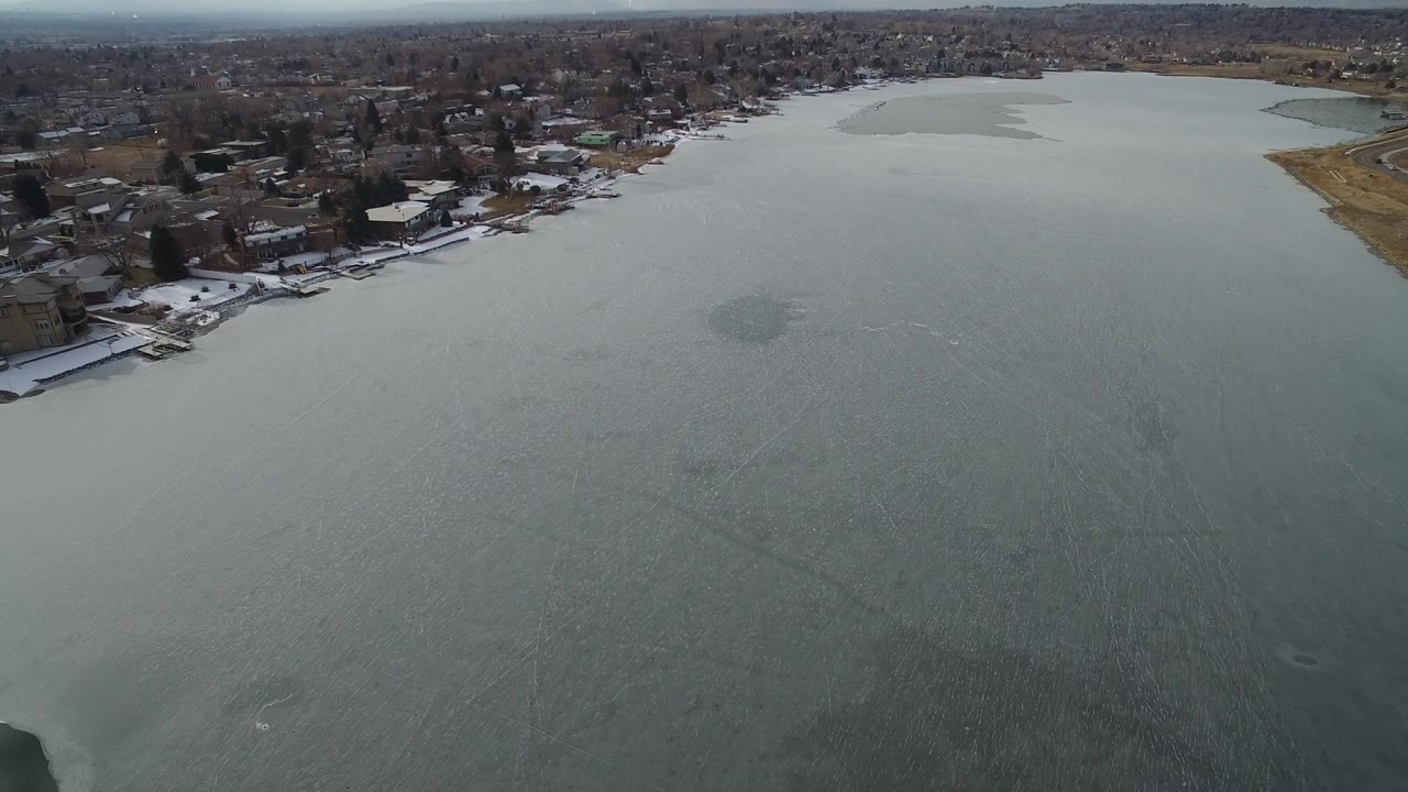 Elevated view over a frozen lake beside a residential shoreline