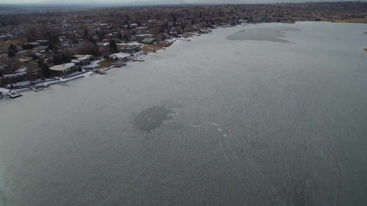 Aerial view over gray water toward shoreline homes.