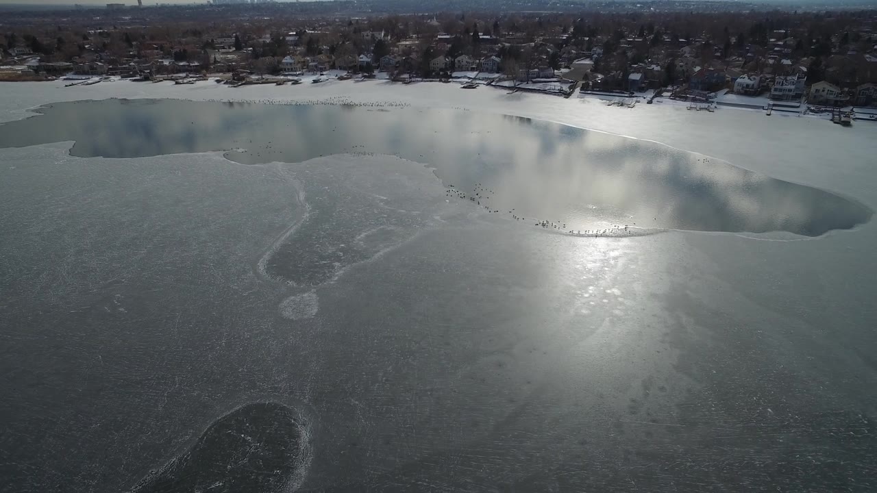 Aerial lake view with a curved open-water edge and winter shoreline.