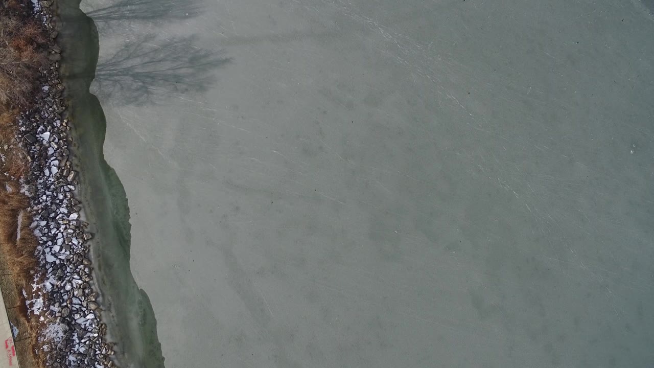 Overhead view of pale water beside a rocky shoreline