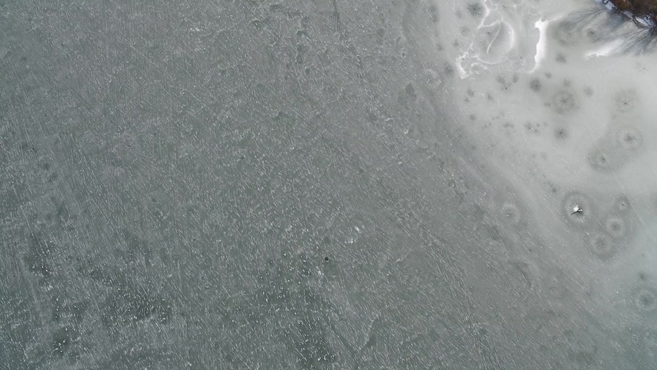 Gray textured surface with pale icy patches and circular marks.