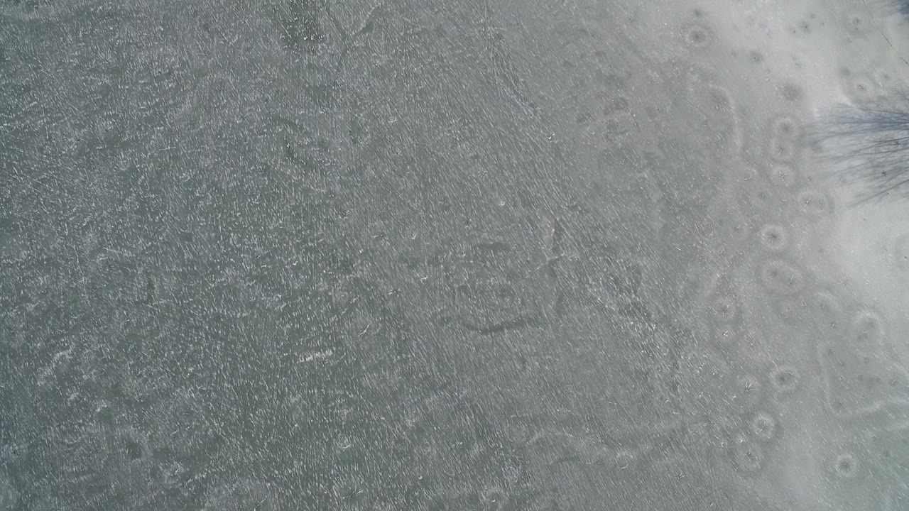 Top-down view of gray-blue ice and pale frozen patches on Hidden Lake in Colorado, with no visible people.