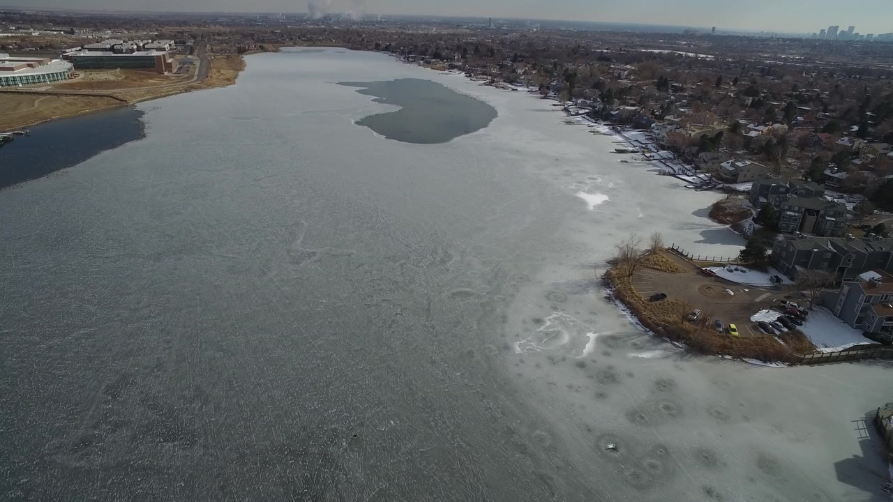 Frozen lake with snow bands and neighborhood shore