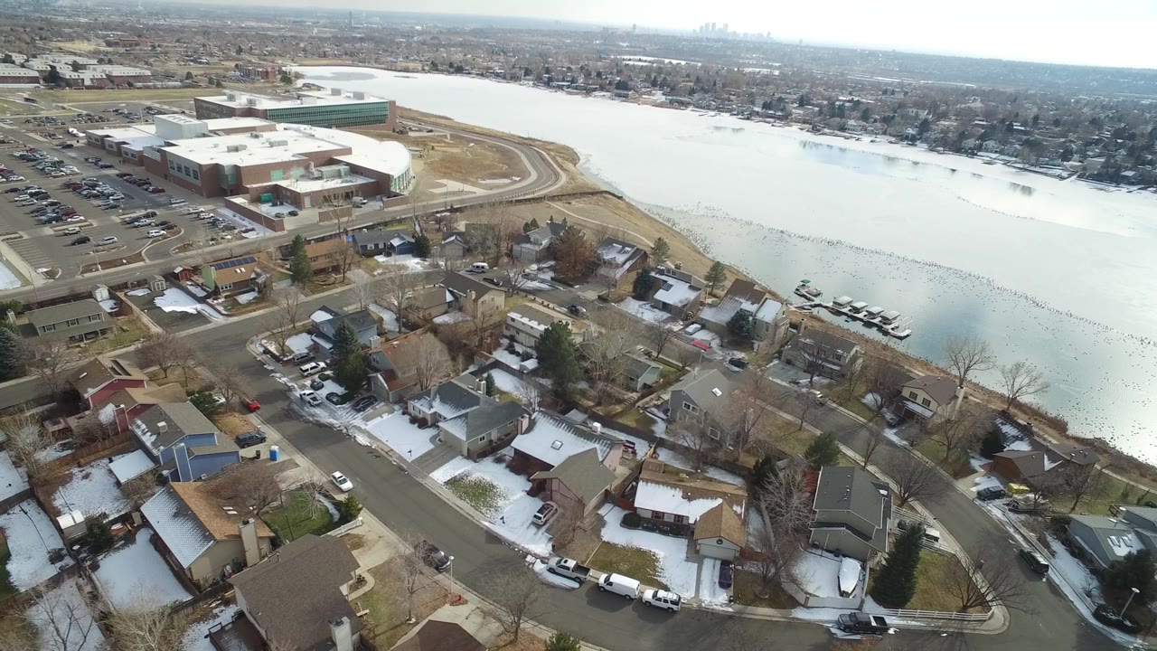 High view of homes and a large building beside pale frozen water.
