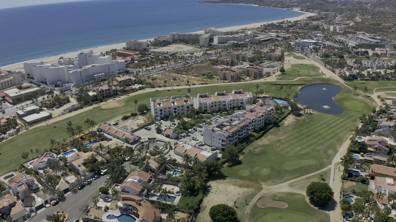 Aerial view of golf fairways, homes, beach, and coastline.