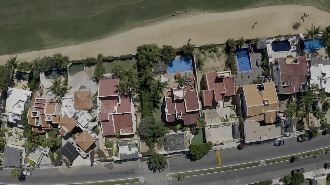 Top-down aerial view of homes beside a green field and road.