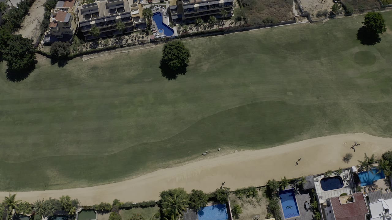 Overhead golf fairway beside homes and pools.