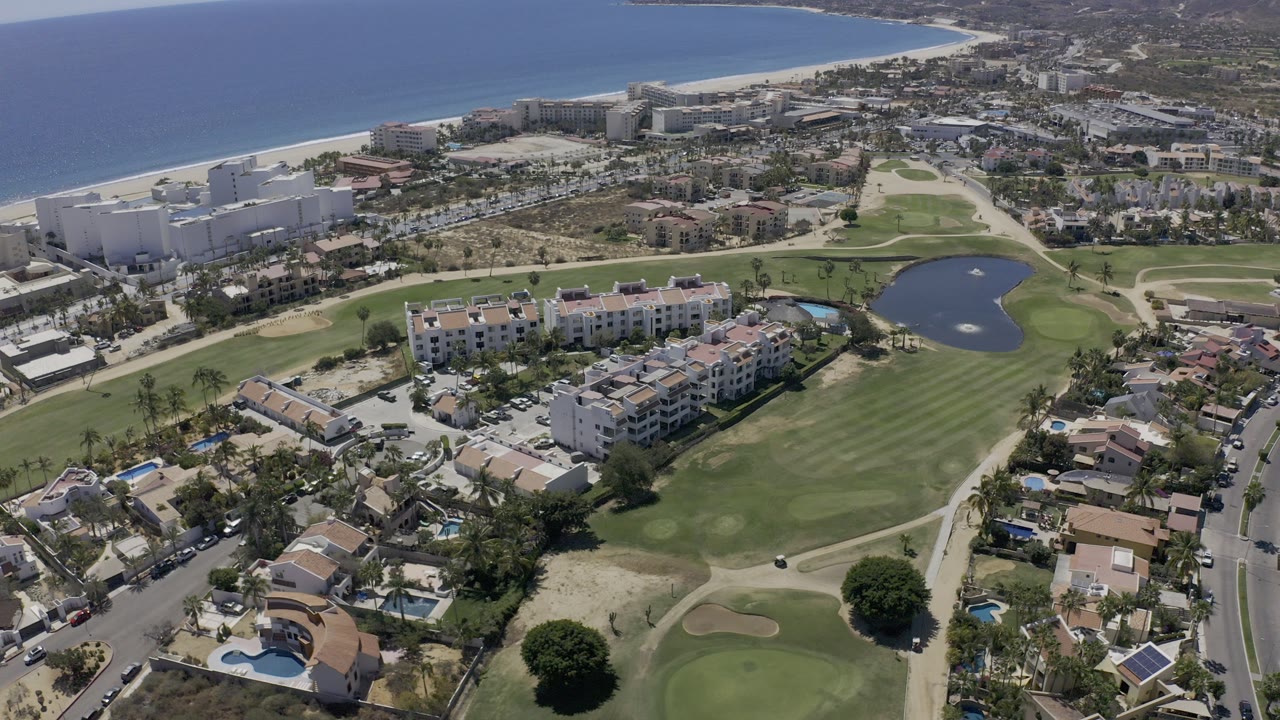 Aerial view of golf course, homes, hotels, beach, and ocean.