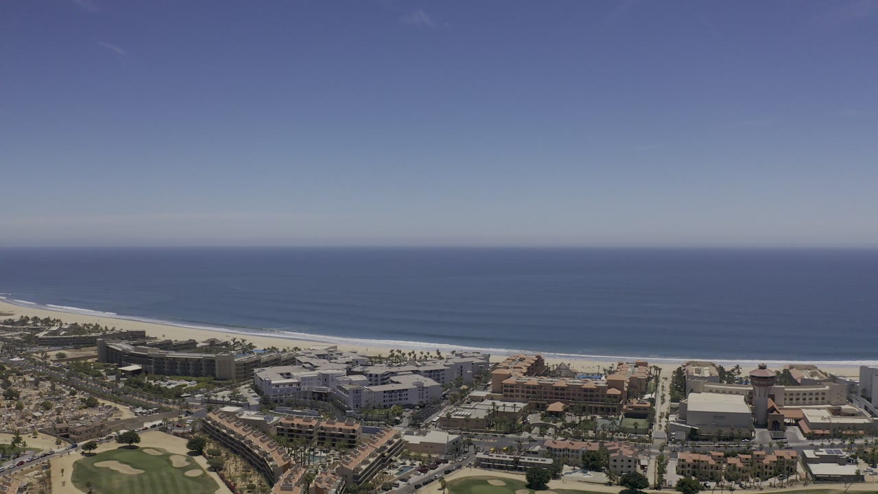 Aerial view of coastal buildings, beach, and open sea.