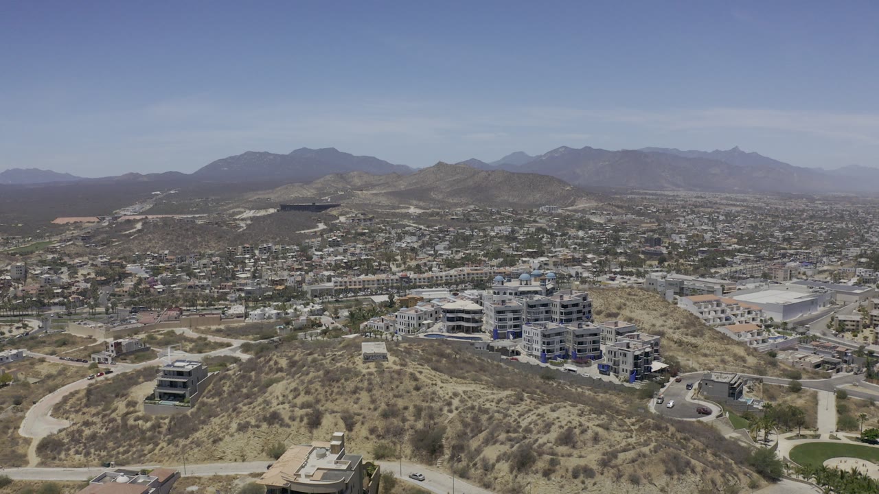 Aerial view of hillside roads, homes, and distant mountains.