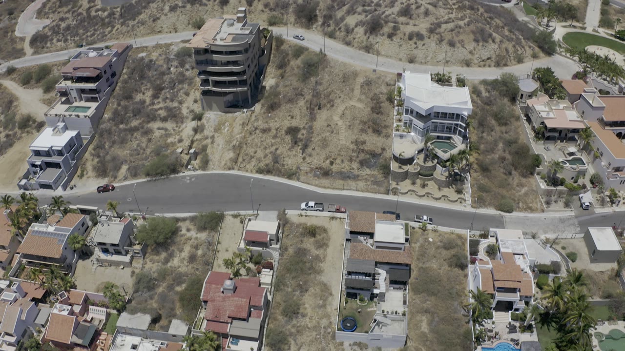 Overhead residential view with modern houses and hillside scrub.