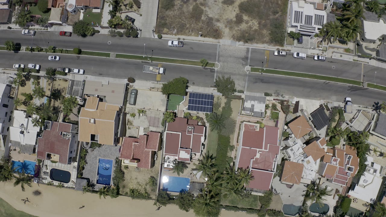 Overhead road traffic beside coastal homes and beach sand.