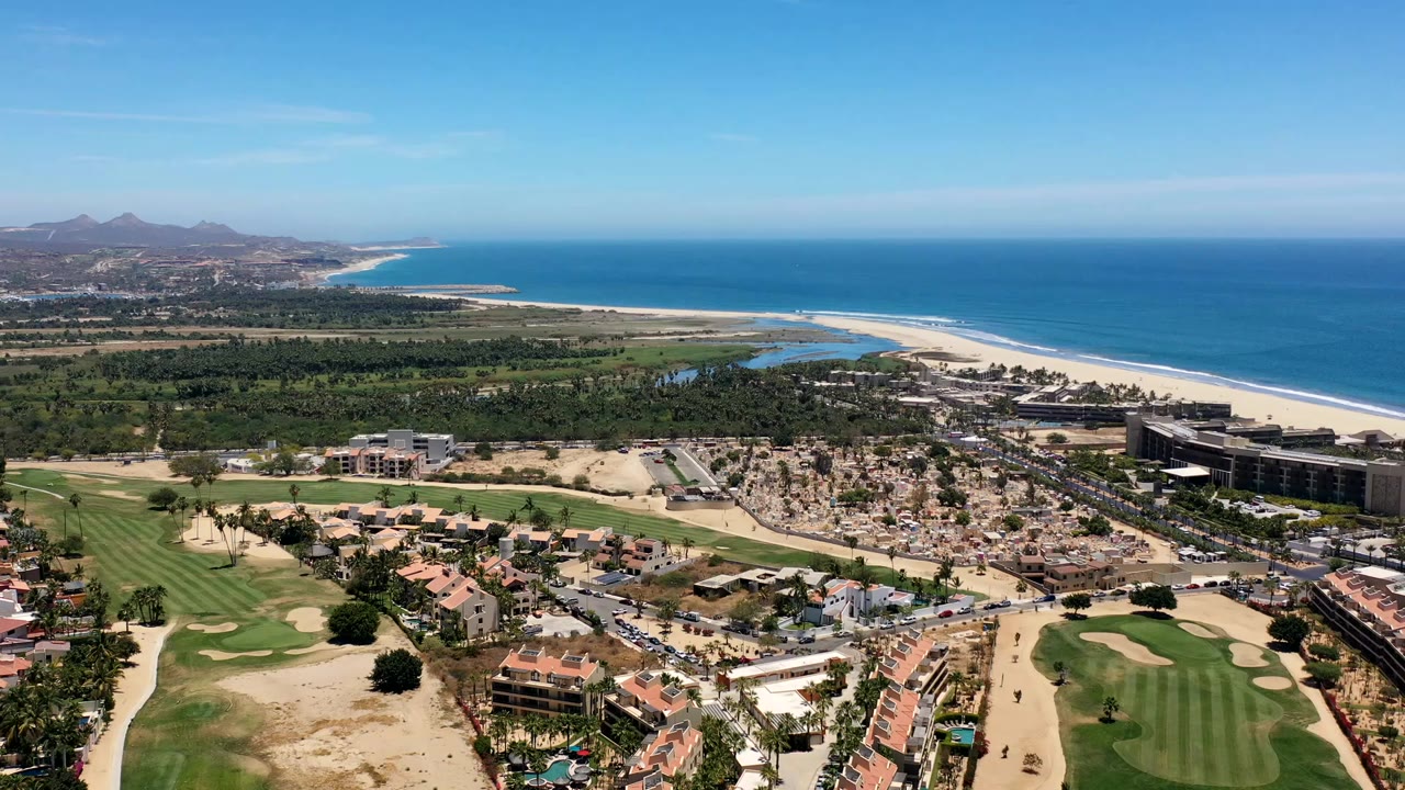 Aerial view of beach, ocean, golf course, and coastal houses.