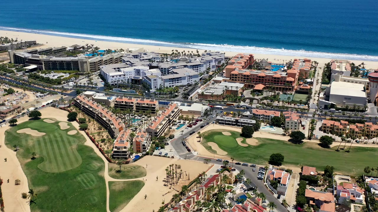 Aerial view of resort buildings, golf course, beach, and ocean.