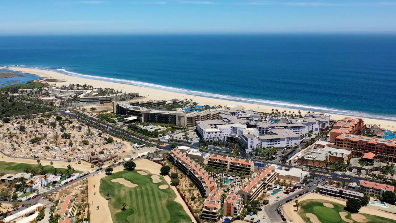 Aerial view of resort buildings, golf course, beach, and ocean.