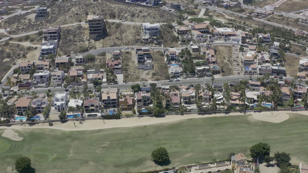 Aerial view of golf course, road, homes, and dry hillside.