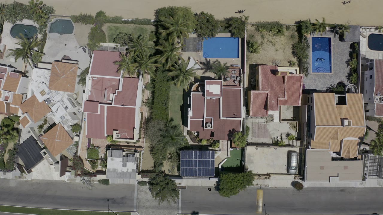 Aerial view of villas, pools, driveways, and empty street.