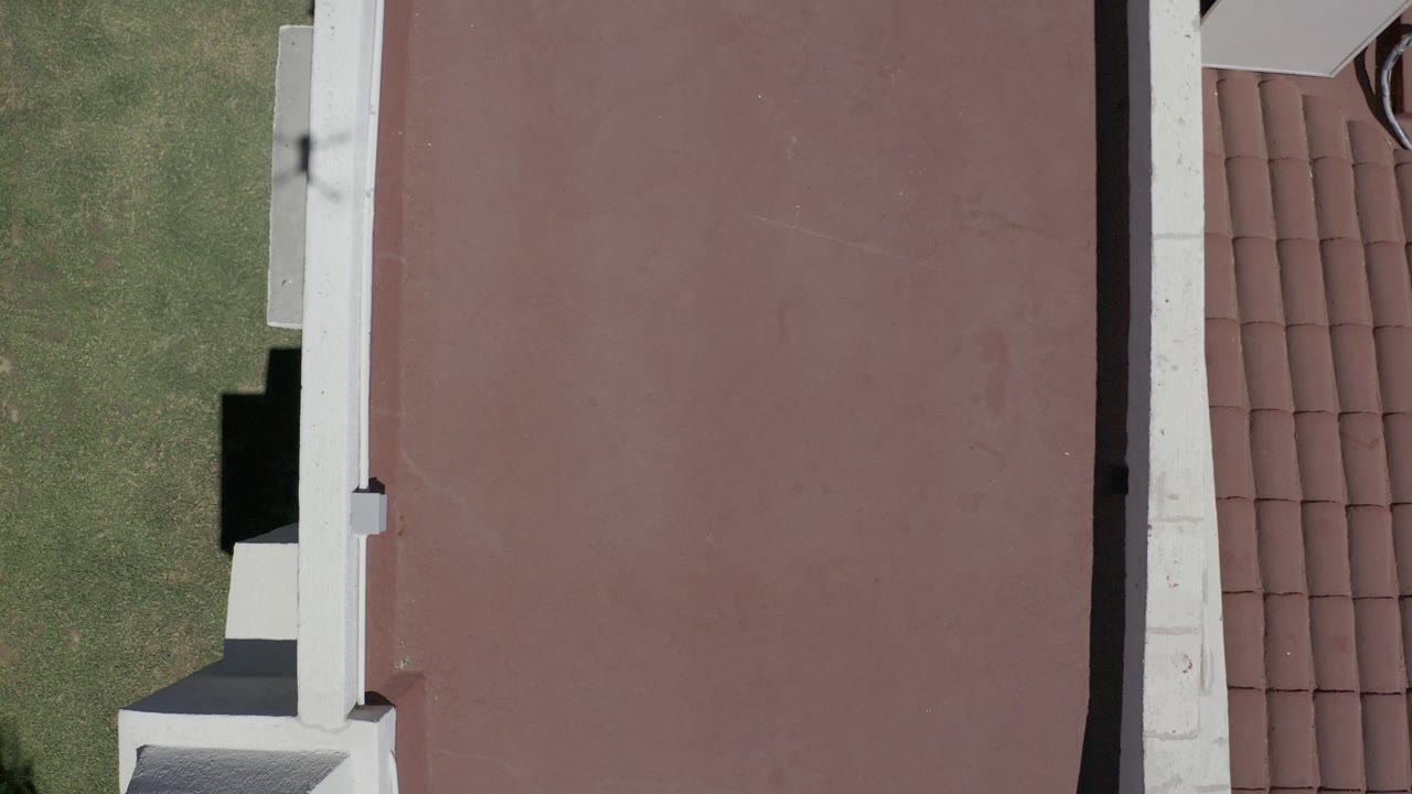 Overhead red roof beside grass and white roof edges.