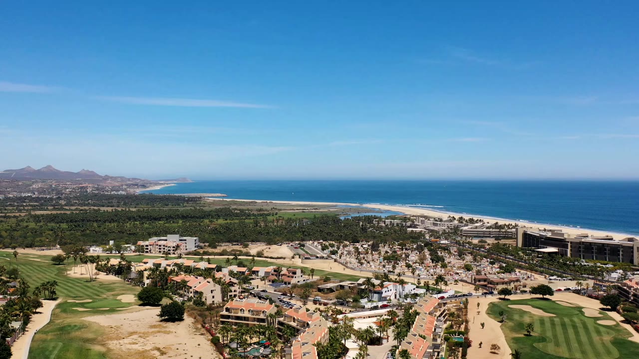 Aerial view of homes, golf greens, beach, and blue ocean.