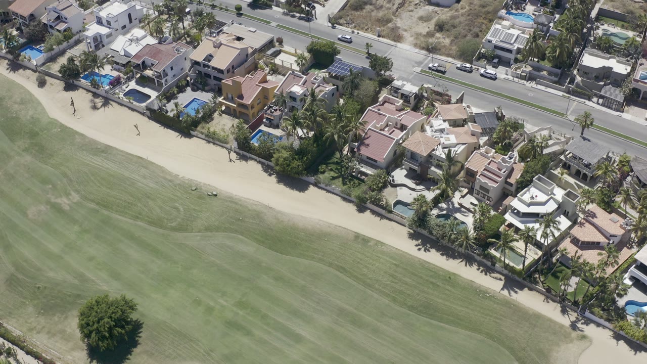 Aerial view of golf course beside residential villas and a road.