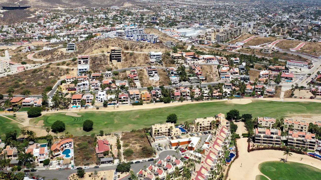 Elevated view of fairways, sand bunkers, villas, and hillside streets.