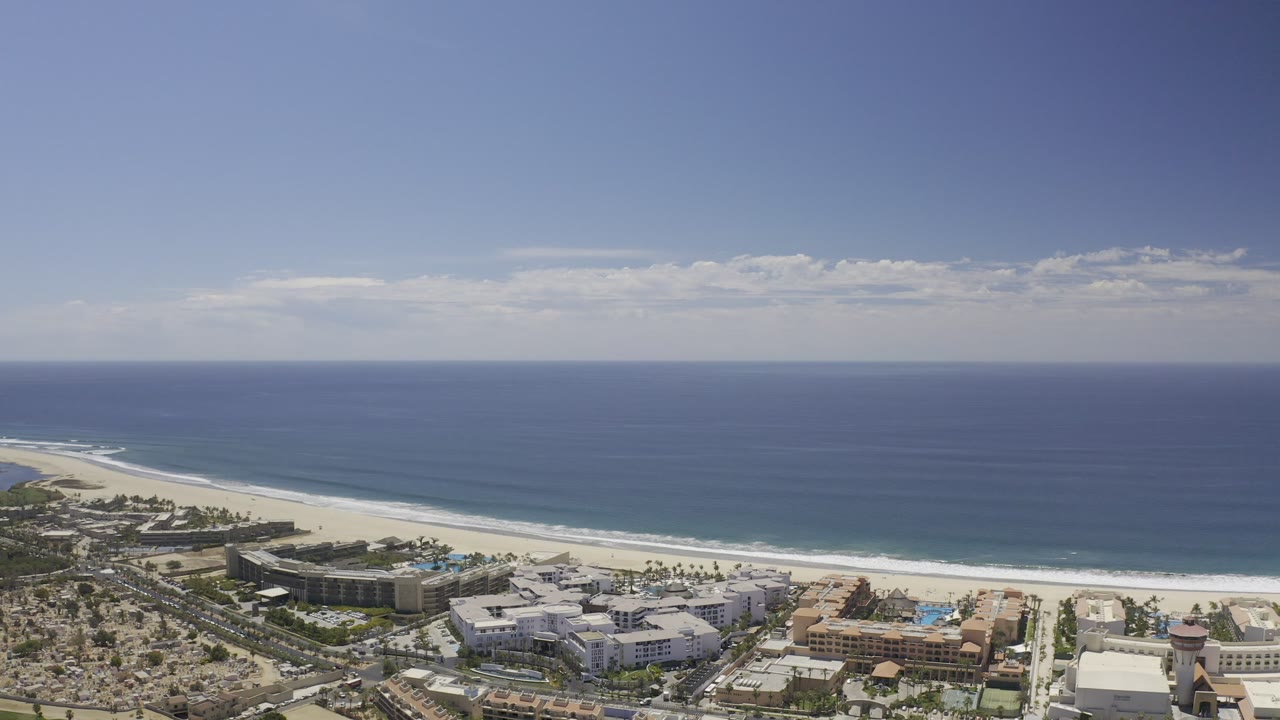 Aerial view of ocean, sandy beach, resort buildings, and coastal roads.
