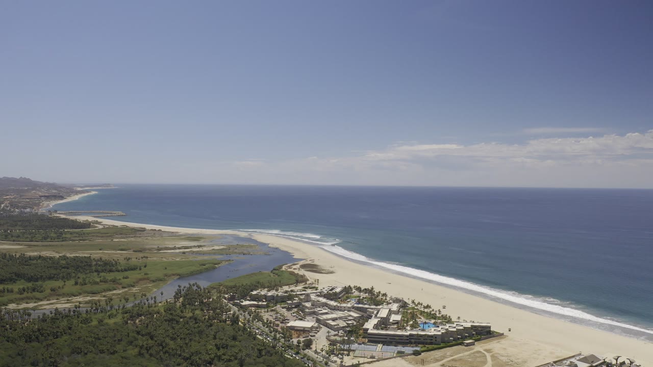 Resort beach aerial with blue ocean, white surf, and inland lagoon