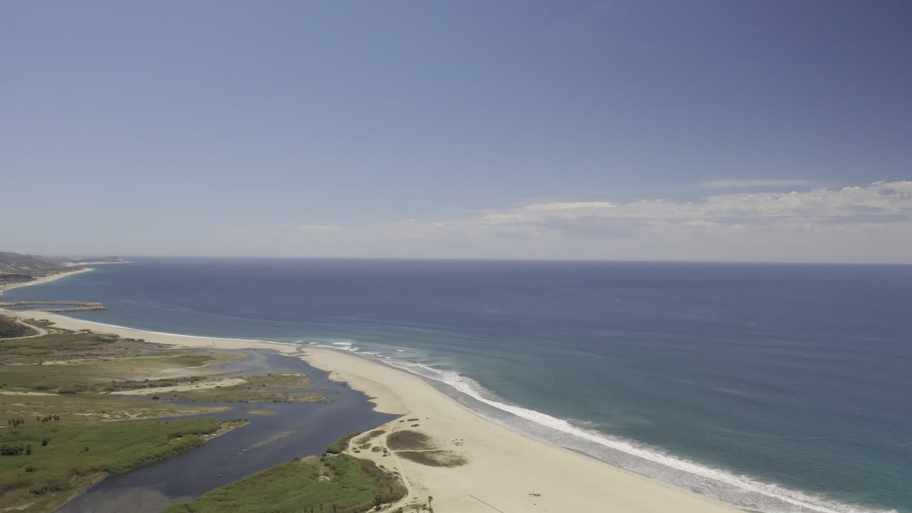 Aerial view of sandy beach, blue ocean, inlet, and coastline